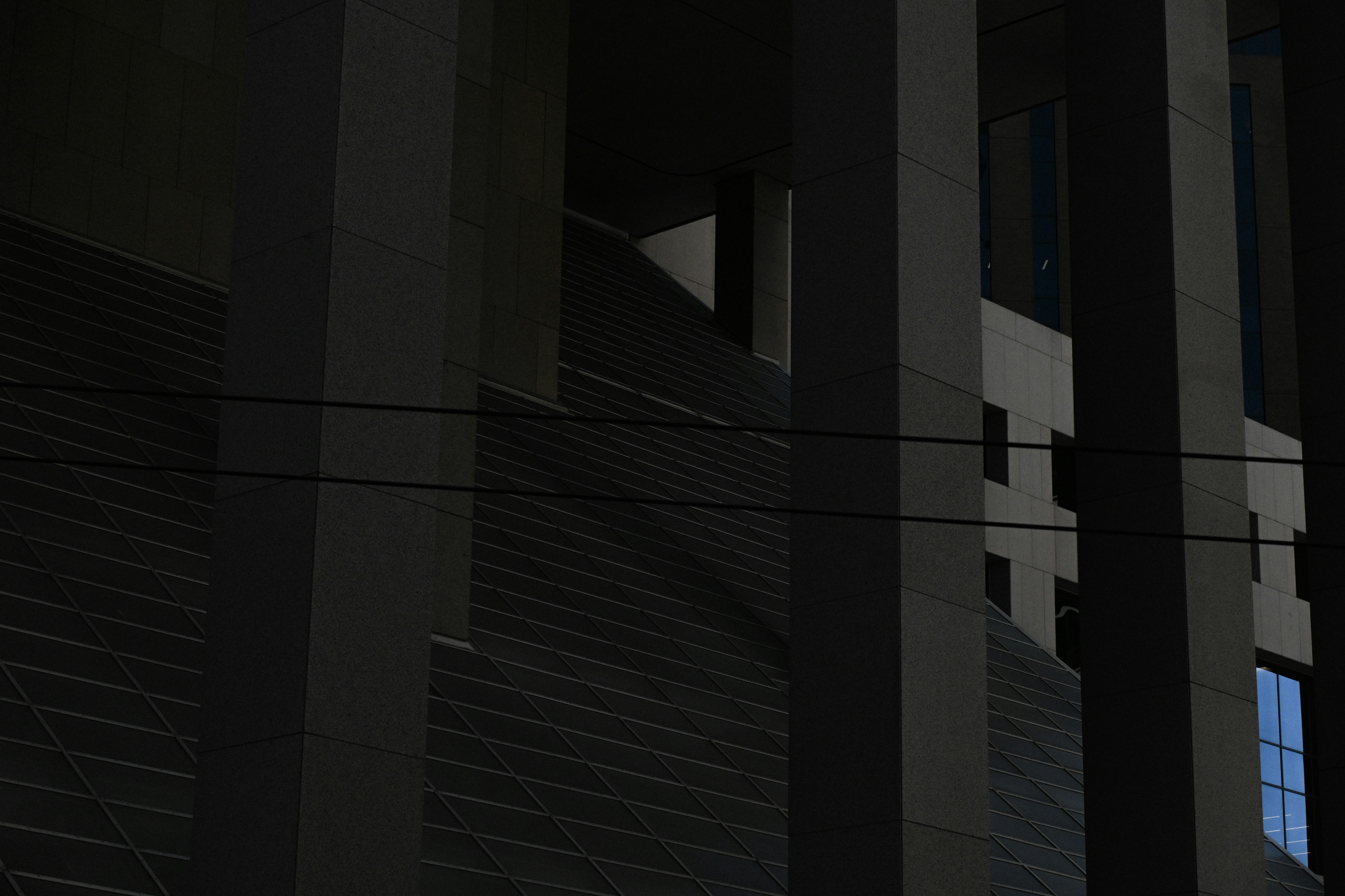 建築現場で、ヘルメットを被り、資材を担いで階段を上る作業員の背中