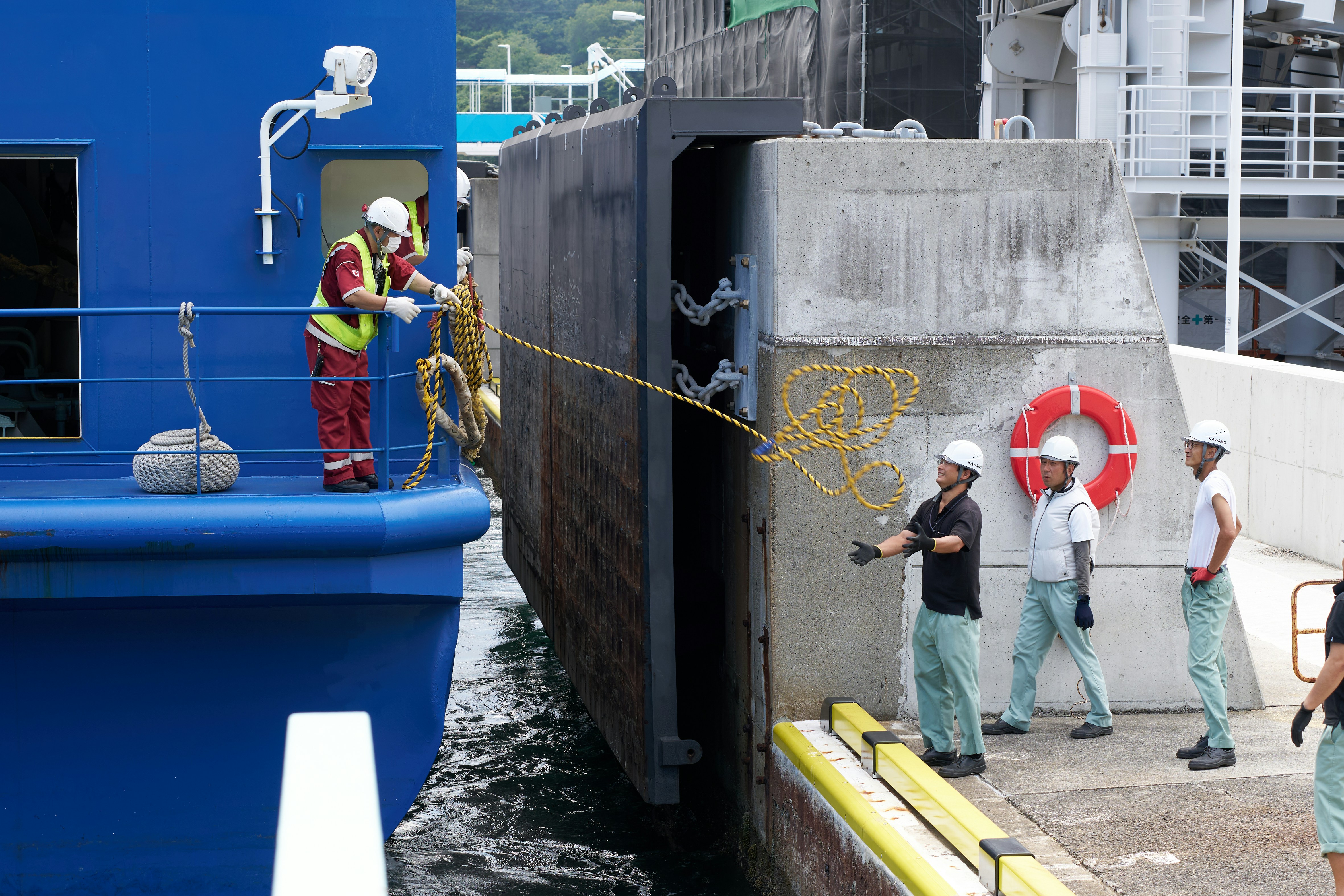 作業員が腰痛ベルトを装着し、石膏ボードを運んでいる様子