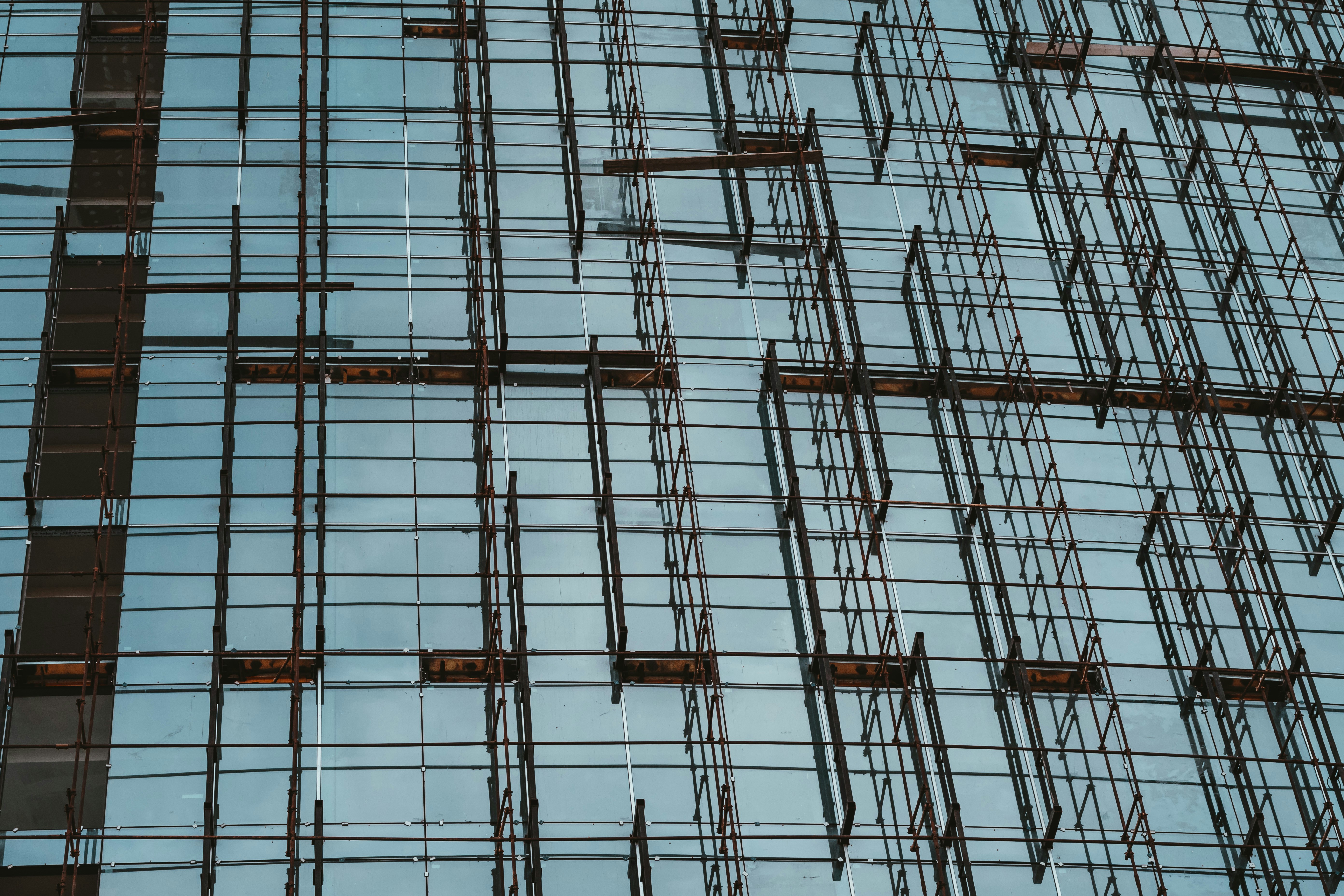 建築現場で、石膏ボードを肩に担ぎ、階段を上る作業員の背中